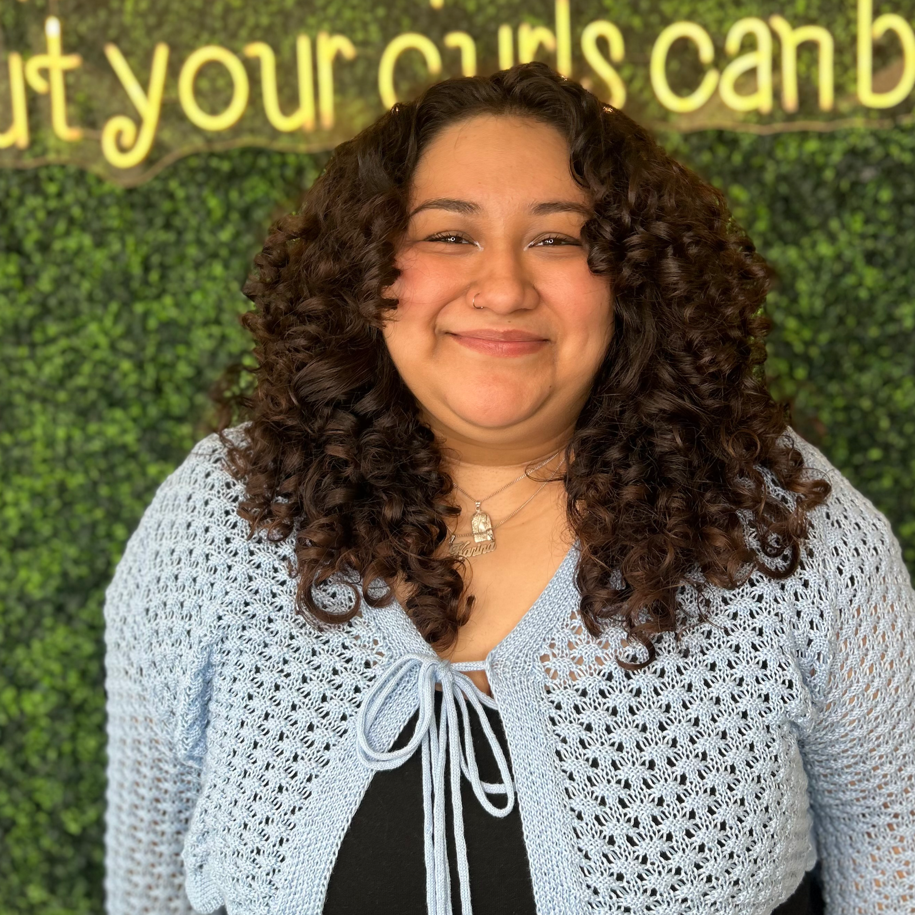Person wearing a light blue knitted shrug in front of a green wall with motivational text.